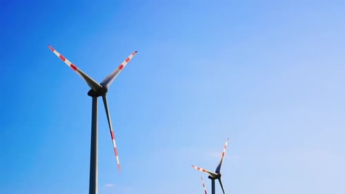 Turbines rise blue sky high.