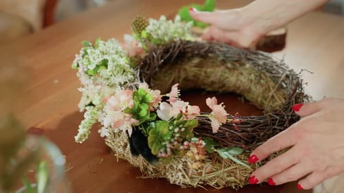 Woman Arranging Elegant Floral Wreath on Wooden Table