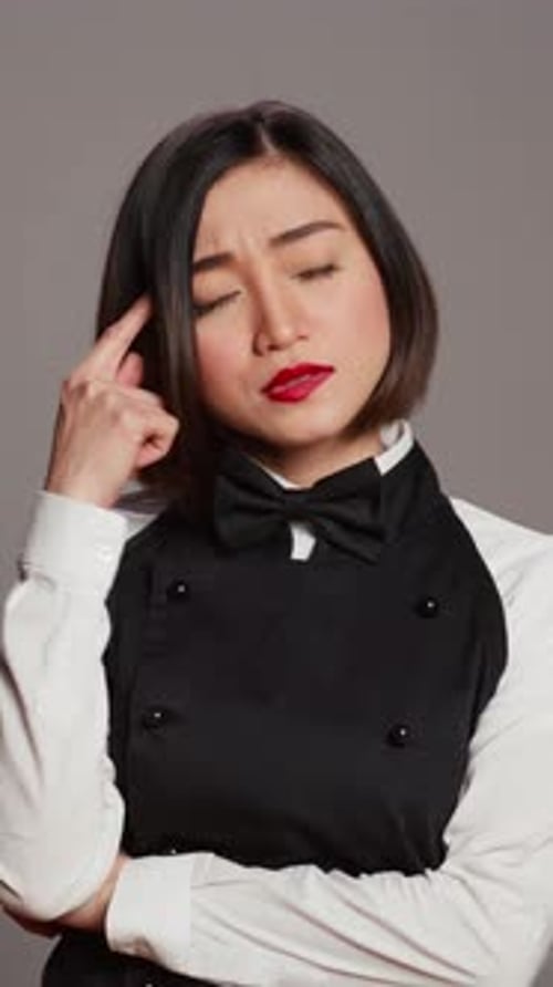 Vertical Video Restaurant Hostess Being Thoughtful Over Grey Background