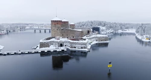 Drone descending in front of the snowy Olavinlinna castle in Savonlinna, Finland