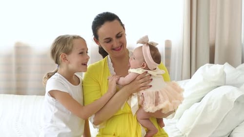 Маленькая девочка с матерью трогает ребенка в спальне