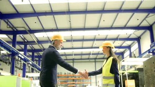 Industrial Man And Woman Engineers In A Factory, Shaking Hands.