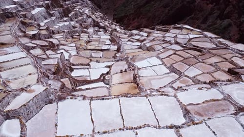 Salt Mines of Maras in the Sacred Valley of Peru, aerial dolly above rock lined pools