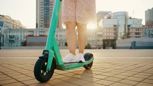 The Girl Pushes Off and Starts Riding an Electric Scooter Around the City