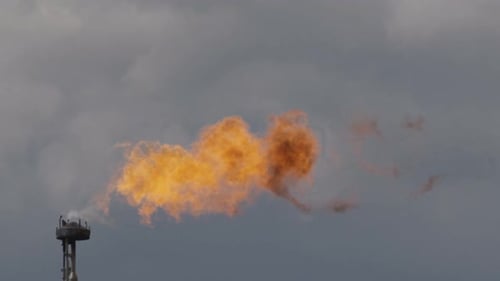 Large Flame on Tower Among Gray Clouds Aerial View