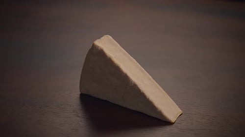 Hand Picks Up Cheese Wedge on Wooden Table
