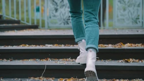 Young Woman in Fashionable White Boots Going Up the Stairs in the Park Back View Seasonal Style
