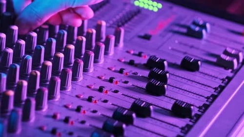 Sound Engineer Moves Faders Up and Down on Audio Mixer in Neon Light CloseUp