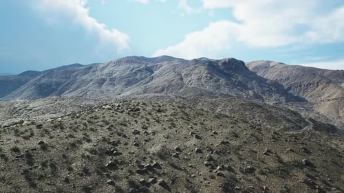 Paisaje montañoso bajo un cielo brillante con nubes dispersas