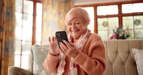 Senior Woman Smiling at Phone on Couch
