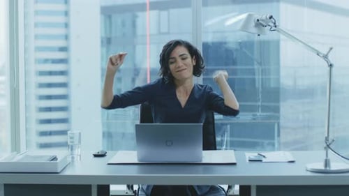 Enthusiastic woman celebrating success at office desk