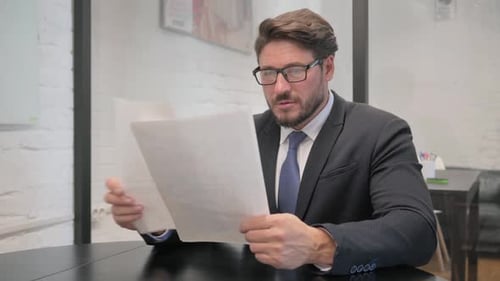 Professional Man Reading Documents in Modern Office