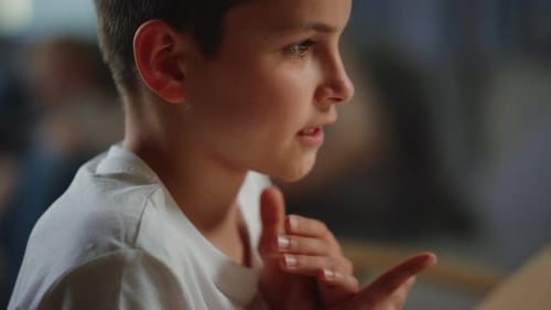 Porträt eines süßen Jungen, der während des virtuellen Unterrichts drinnen mit der Hand winkt. Lächelnder Schuljunge