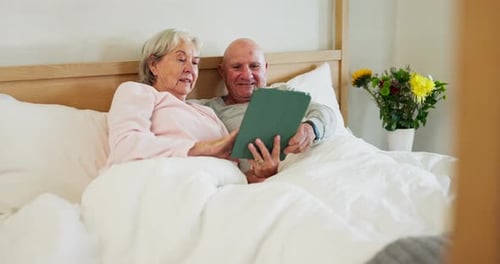 Senior Couple Relaxing in Bed with Tablet