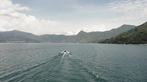 Motorboat sails on Atitlan lake, Guatemala. Aerial ascending reverse
