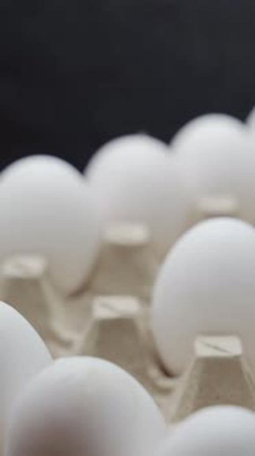 Eggs are getting put into carton tray. Crates of fresh eggs at a poultry farm. Vertical video