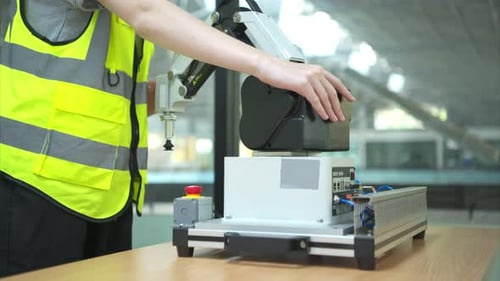 Hand pressing the stop button on the control panel of an industrial machine.