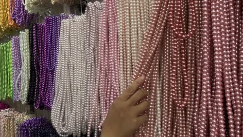 Une exposition de colliers de pierres précieuses multicolores accrochés à un cintre en fer