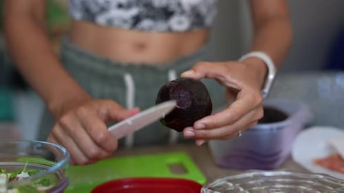 Woman Peeling Vegetable with Knife in Kitchen