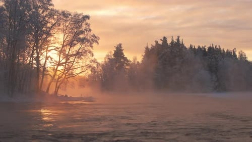 Beautiful cold winter morning by a steaming river during golden hour sunrise. Tripod shot.