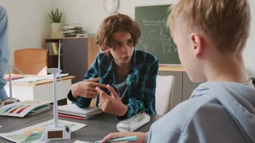 Students Discussing Renewable Energy in Classroom with Wind Turbines
