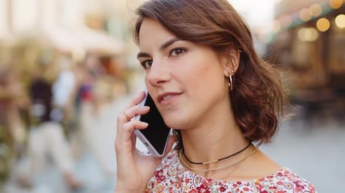 Une jeune femme heureuse ayant une conversation à distance parlant sur un smartphone Bonne nouvelle, potins dans la rue de la ville
