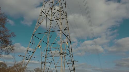 Electricity pylon in the middle of a barren farmers field with cables stretching across the countrys