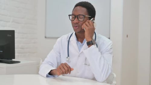 Young African Doctor Talking on Phone in Clinic