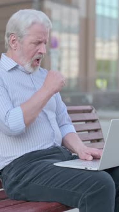 Senior Man Uses Laptop Outside and Coughs
