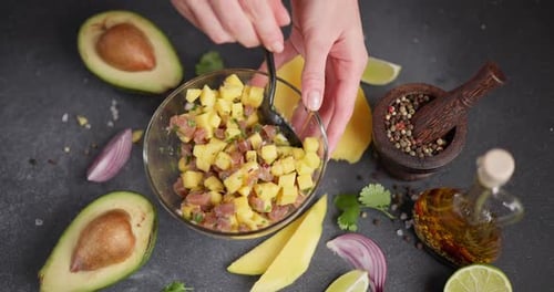 Woman Mixing Chopped Tuna Mango Cilantro and Onion in a Glass Bowl Cooking Traditional Tuna and