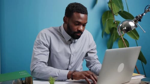 A Focused Professional is Engaged in Work on a Laptop in a Contemporary Office Environment