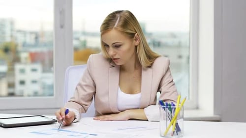 Businesswoman works with tablet and financial documents in modern office