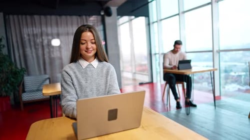 Femme indépendante travaillant sur son ordinateur portable assise au bureau. Travaillez à distance dans un espace de travail confortable.