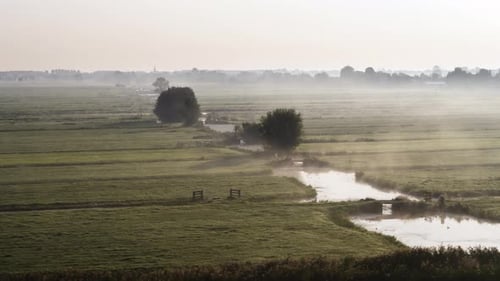 Water canal in middle of majestic misty farmland in Holland, aerial view