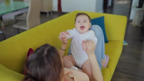 Woman Playing with Infant on Couch at Home