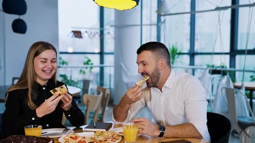 Smiling Couple Eating Pizza at a Restaurant Table