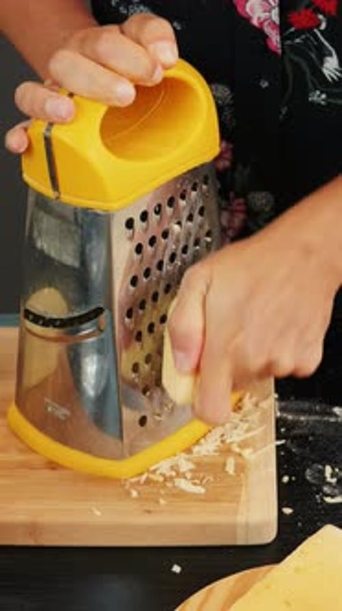 Person Grating Cheese on a Wooden Cutting Board