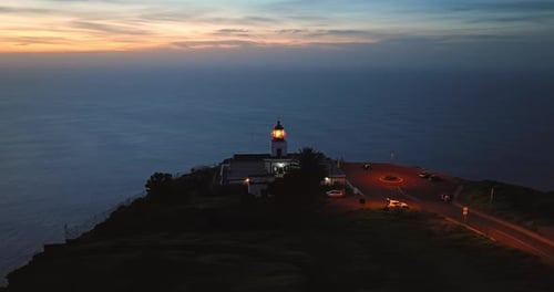 Luftaufnahme des funktionierenden Leuchtturms in der Abenddämmerung auf einem malerischen Felsenleuchtturm Ponta Do