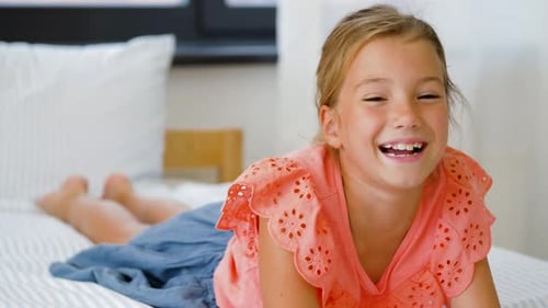 Happy Child Smiling While Lying on Bed Indoors