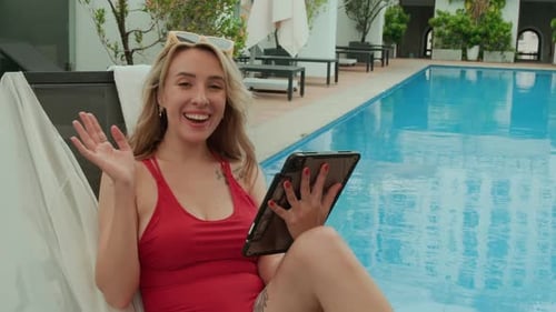 Caucasian Woman Using Tablet while Resting by Pool during Summer Vacation