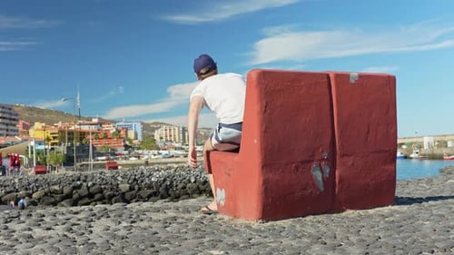 Tourist stands up from a cement beach chair with view on Candelaria, Tenerife