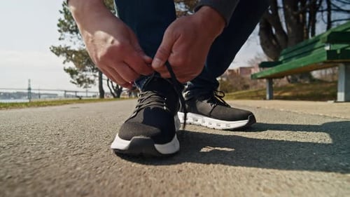 Slow Motion Man Tying His Shoelaces While Walking Down An Alley At Sunset