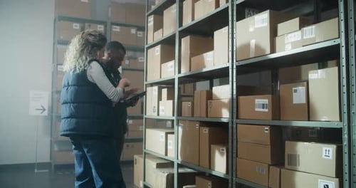 Multiethnic Warehouse Workers Using Tablet Computer Checking Inventory