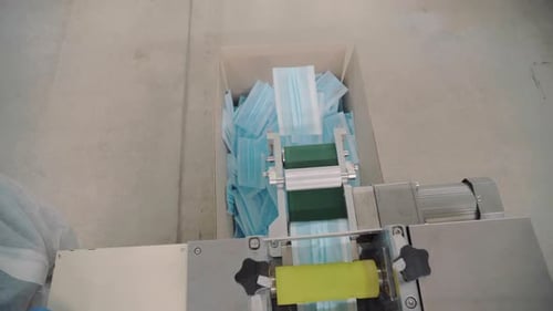 Medicine face mask factory. Face mask conveyor line. The masks fall from the conveyor line into the
