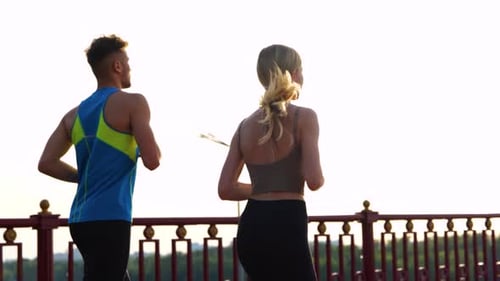 Active Young Couple in Sportswear Enjoy Running Outdoors on the Bridge Man and Woman Running Across