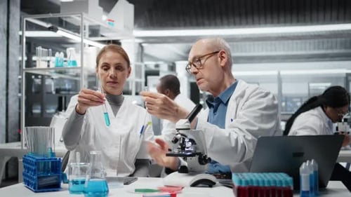 Chef d'équipe de laboratoire enseignant à un stagiaire l'analyse des propriétés des polymères liquides