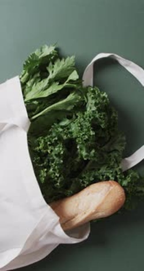 Vídeo vertical de bolsa de lona negra con perejil, col rizada y baguette, espacio para copiar sobre fondo verde