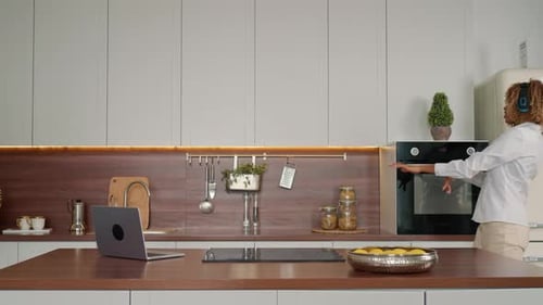 Blonde Woman Dances to Music in Modern Kitchen