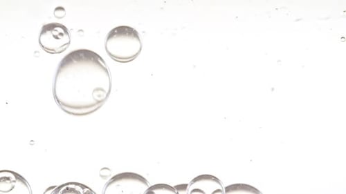 Bolhas transparentes se formam e flutuam para outras em uma superfície transparente sobre fundo branco O medicamento