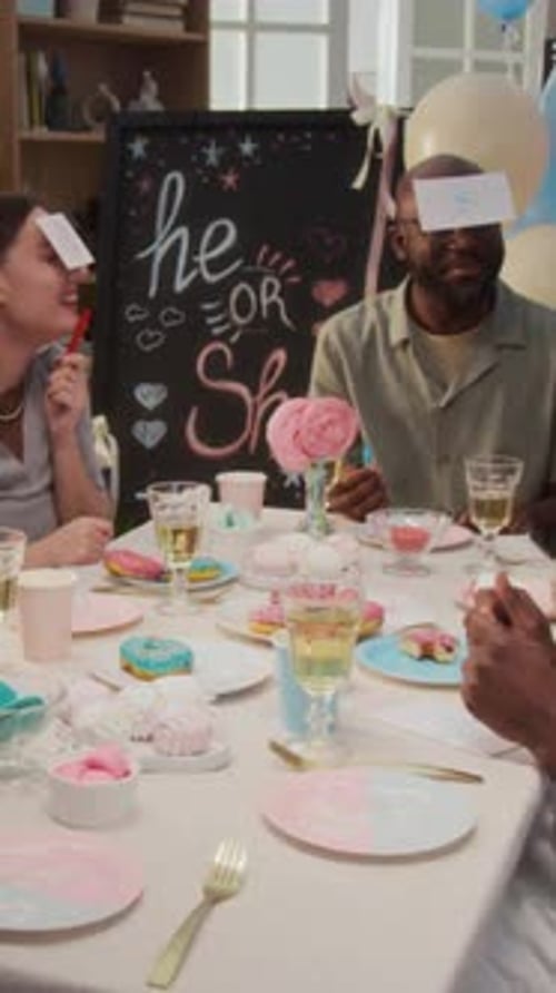 Vertical of Positive Expecting Couple Playing Game and Laughing at Sweet Table